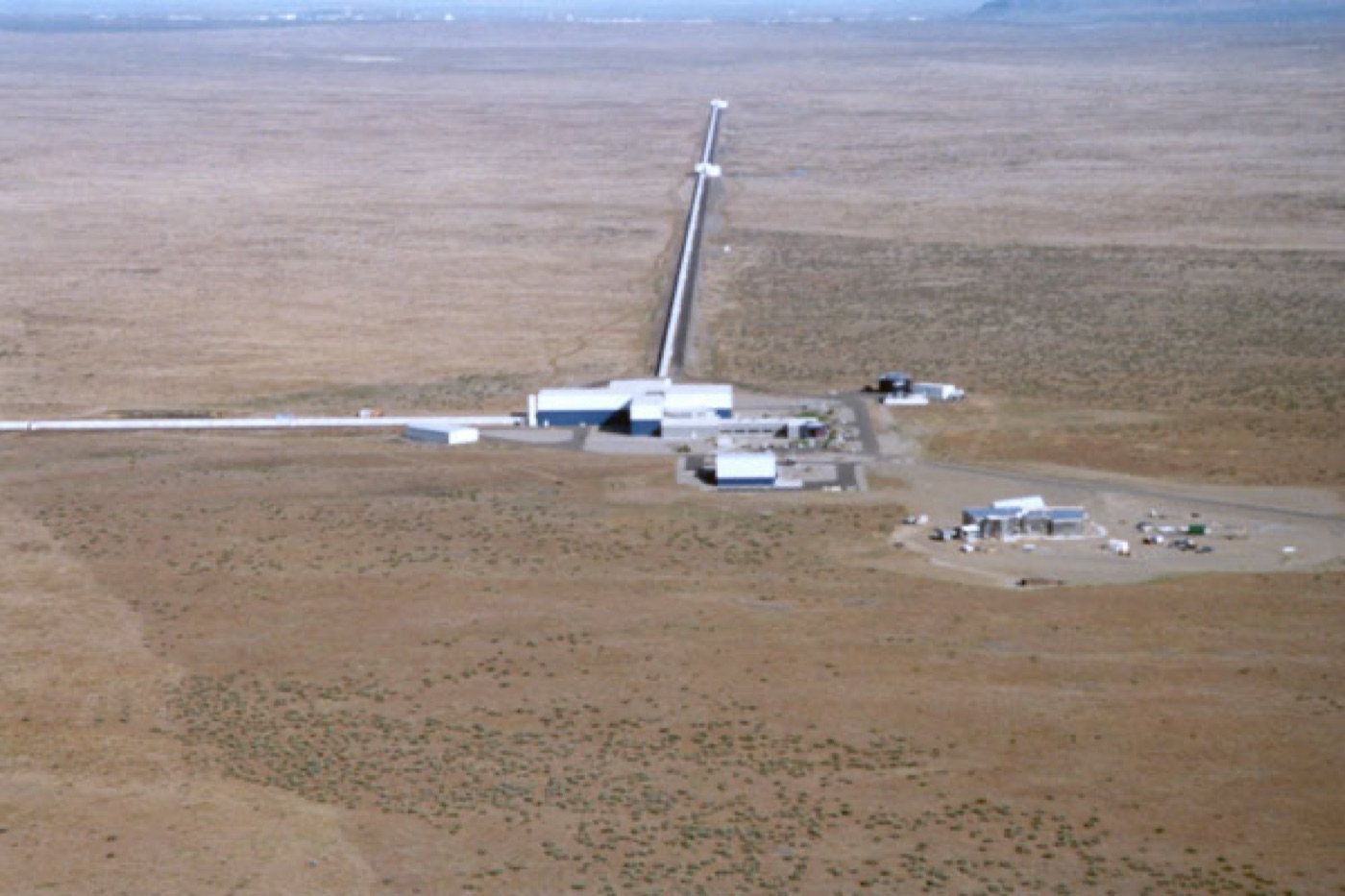 Aerial view of the LIGO Hanford observatory: two long perpendicular vacuum-tube arms stretching kilometres across the desert from a central building
